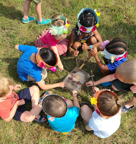 Children sit in a circle, playing outside