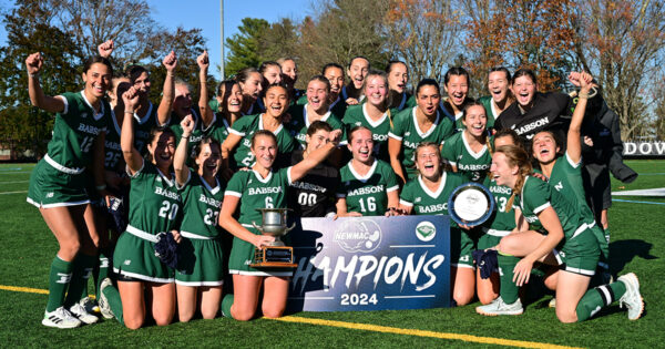 The field hockey team poses for a group photo with the championship banner and trophy