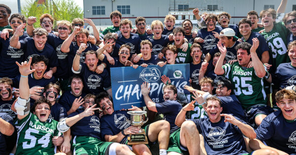 The lacrosse team poses for a group photo with the championship banner and trophy