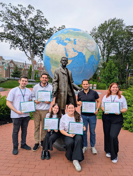 The winning teams pose for a photo in front of the Babson Globe