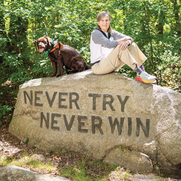 Katherine "Gig" Babson and her dog Flossy sit on the Never Try Never Win boulder