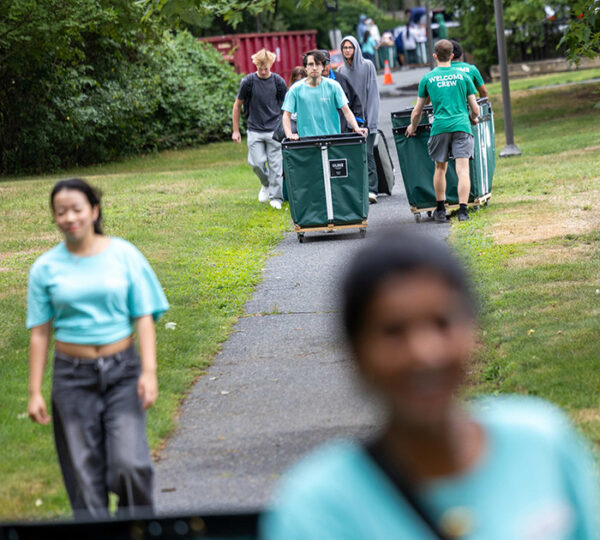 Students roll move in bins on a pathway.