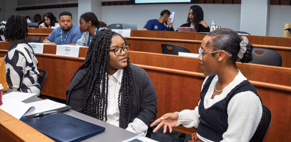 Students talk while sitting in a classroom during Babson Build