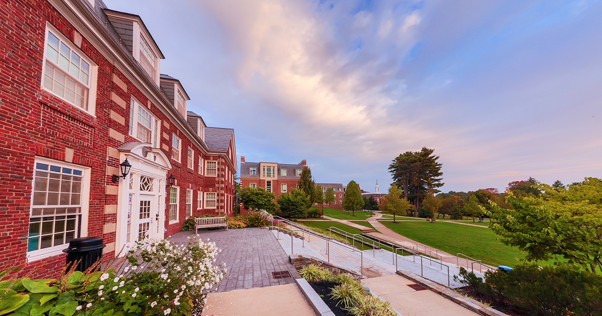 Photo of a campus building at golden hour with a beautiful white cloud amid a blue sky