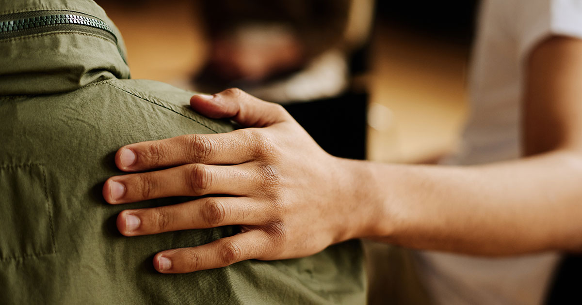 A person puts his or her hand on someone’s shoulder