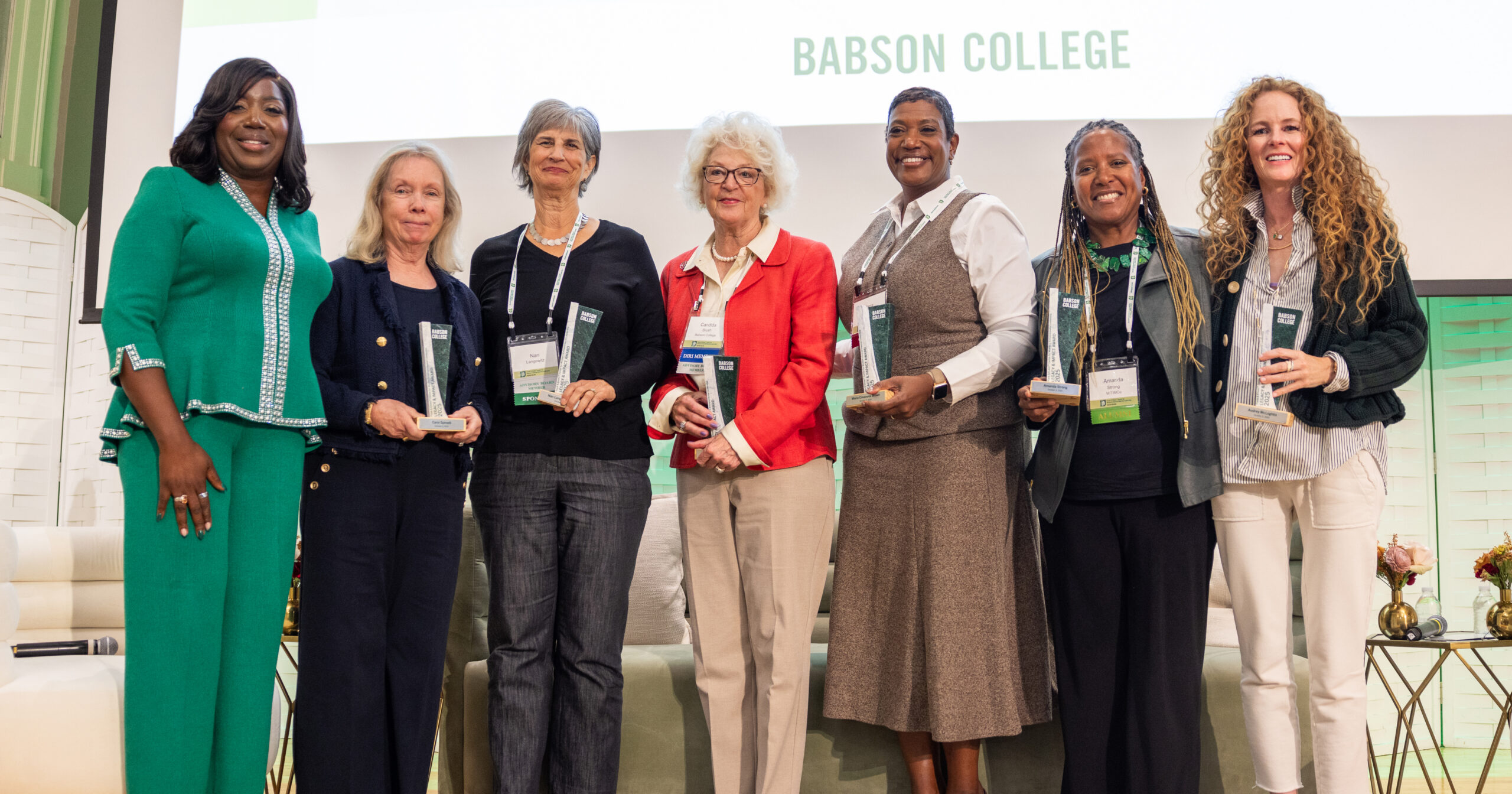 7 women standing on stage holding awards
