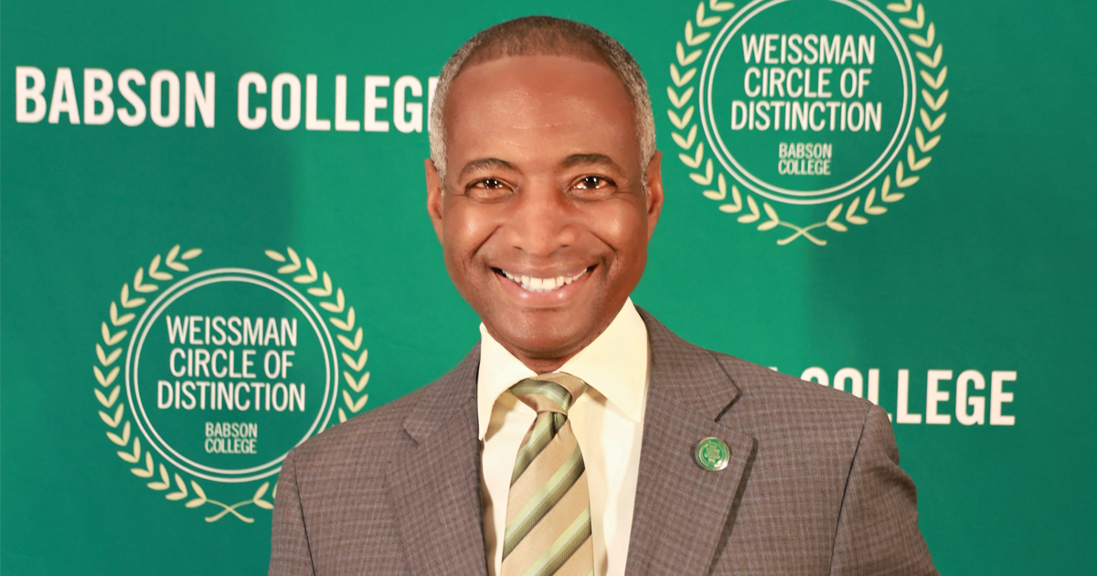 Jeffery Perry poses for a portrait in front of a green Babson background