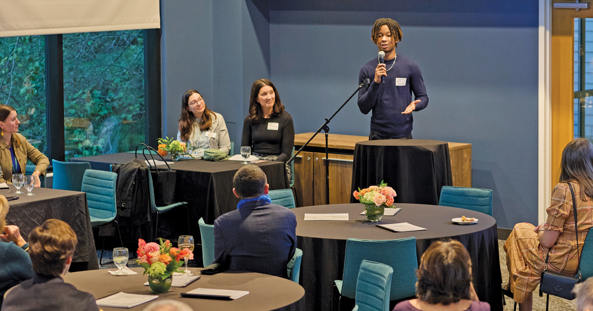 Kaif Bailey in front of a room as attendees at the event