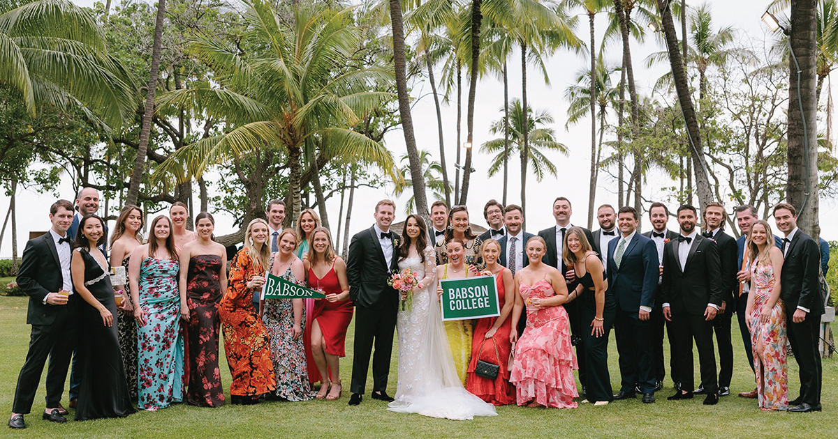 Kyle Morrissey and Taylor Welsh pose for a wedding photo outdoors with a large group of friends
