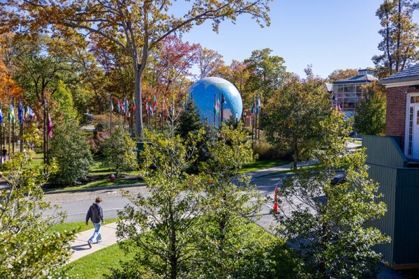 A view from a distance of the Babson World Globe as it sits amid the trees and greens of campus