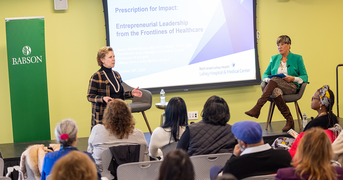 Two women speak in front of an audience