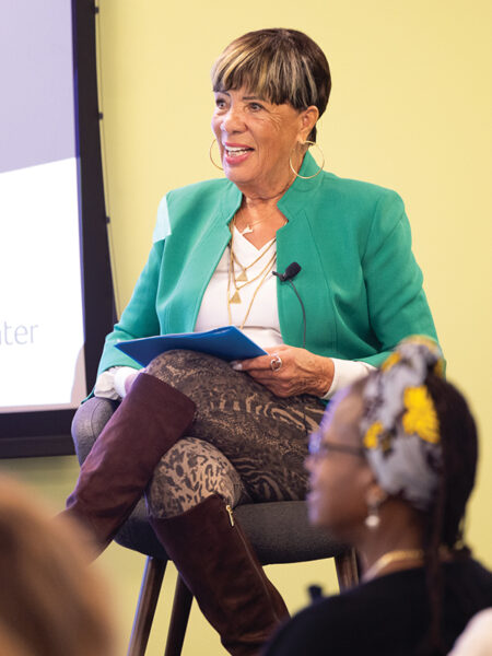 Jane Edmonds sits on stage, moderating a discussion