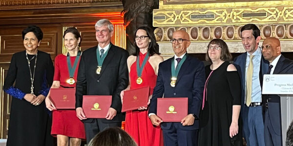 A line of eight people pose for a photo while standing on stage