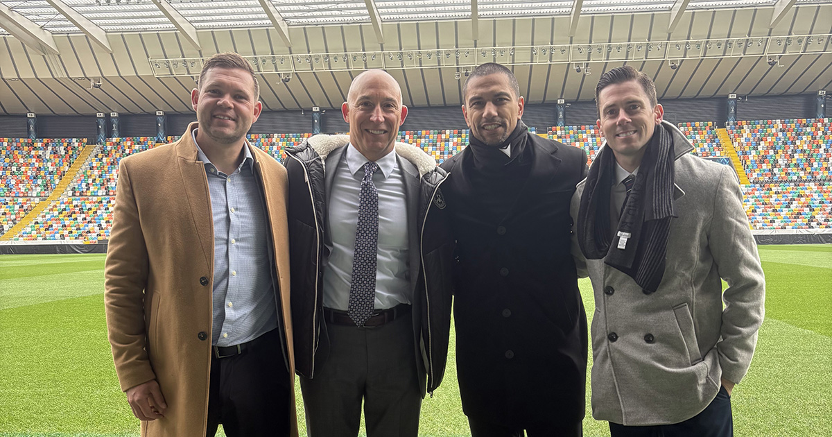 Four people pose for a group photo on the field