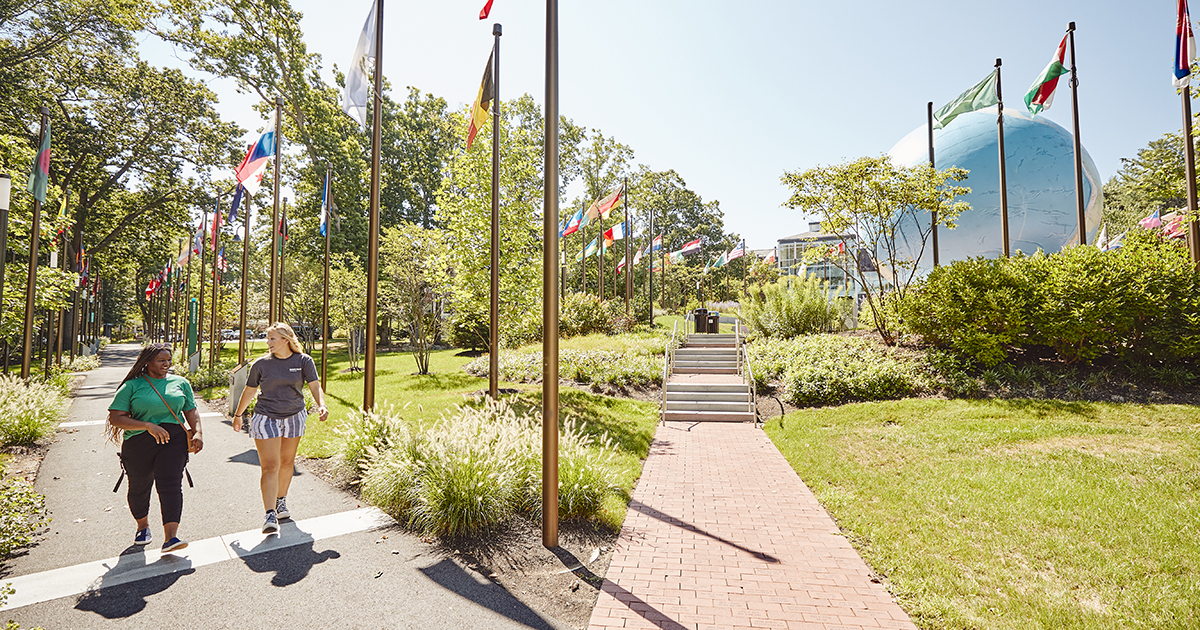 Students walk on campus near the Globe on a bright, sunny day