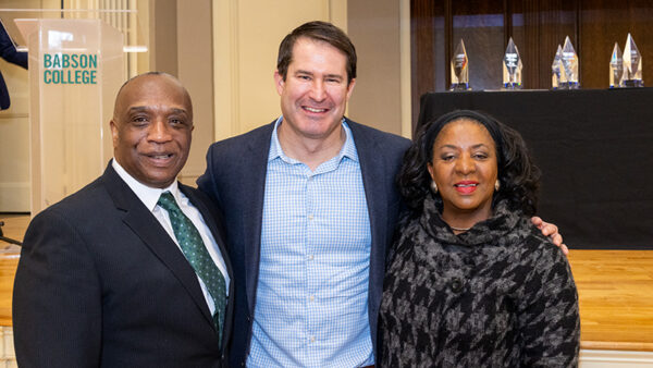 Three people smile while posing for a photo