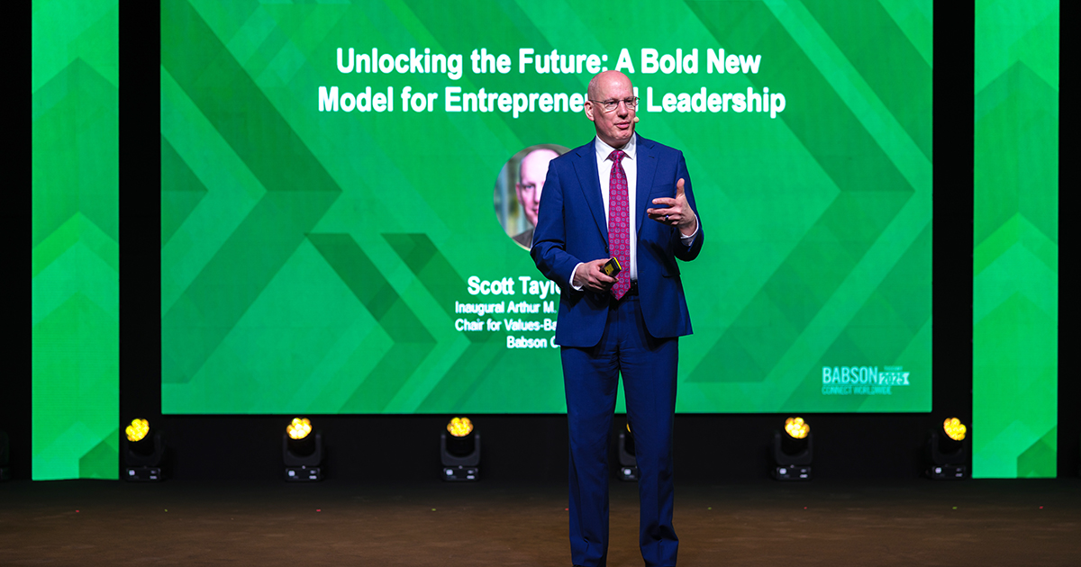 Scott Taylor delivering a keynote address on a green stage