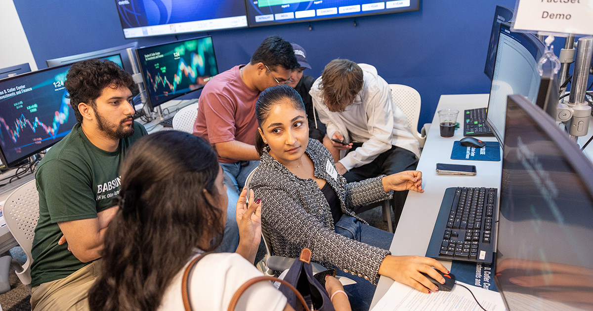 Students collaborate around screens in the finance lab