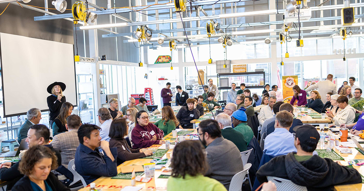 Woman speaks to large crowd gathered for Food Summit in airy room at Babson College.