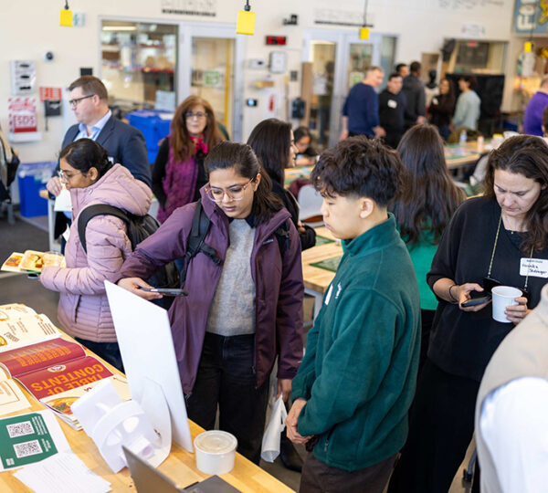 A Babson College student exhibits his food venture in a crowded room.
