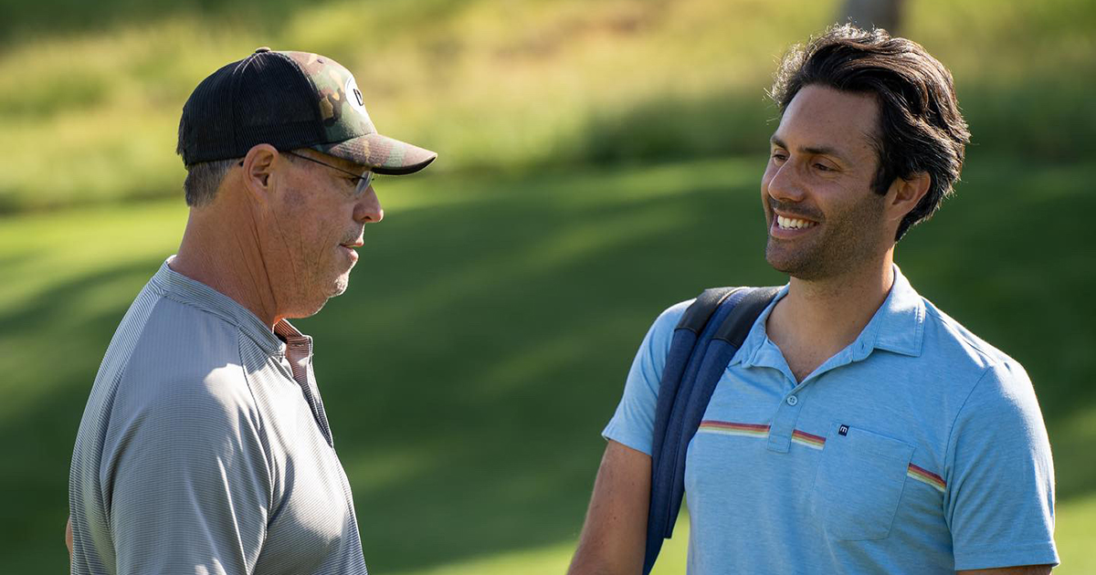 Two smiling men on a golf course.