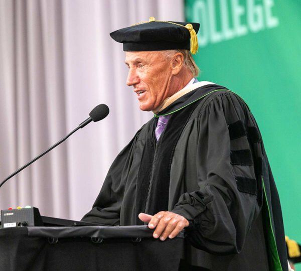 Older man speaks at lectern giving a commencement address.