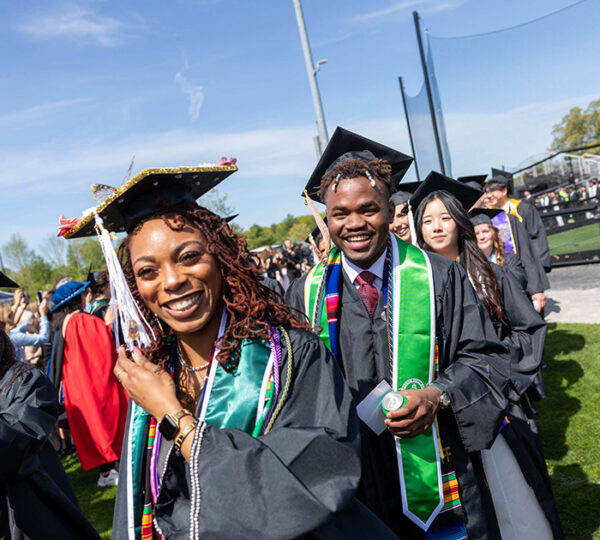 Man and woman in graduation robes celebrating Commencement.