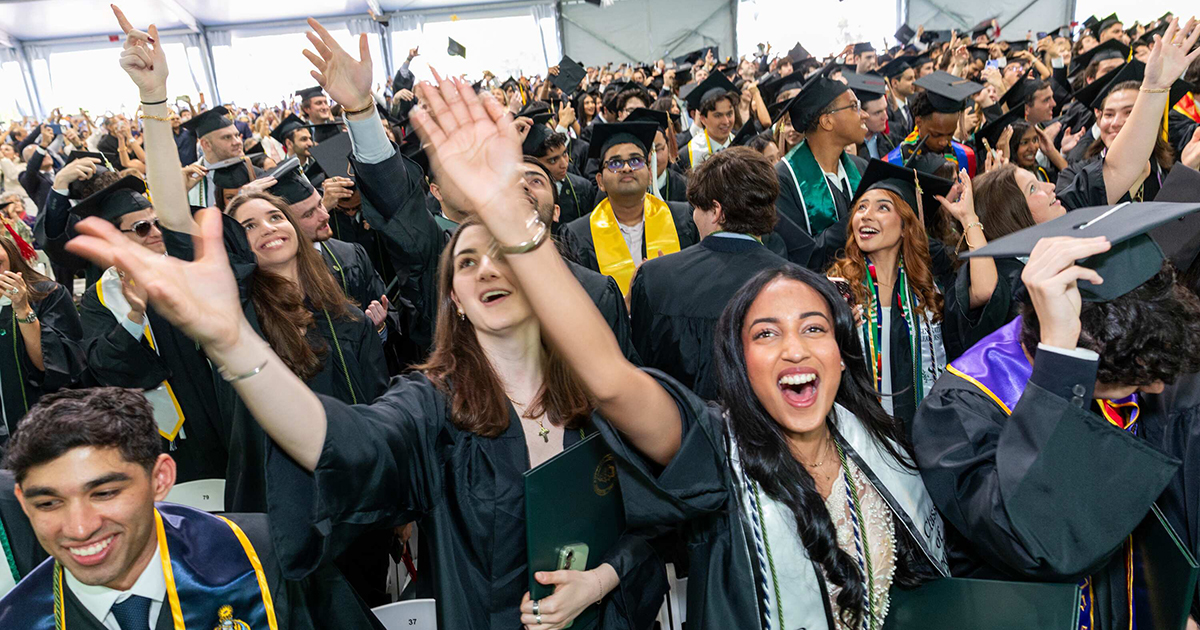 Graduating students toss their caps in the air.