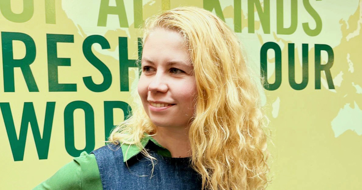 Christelle Brandt stands in profile against a wall with bright, large words on it