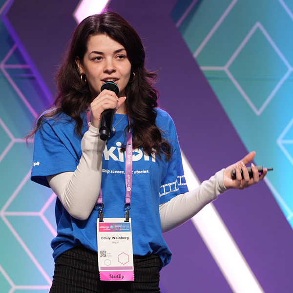 Emily Weinberg speaks while holding a microphone on stage