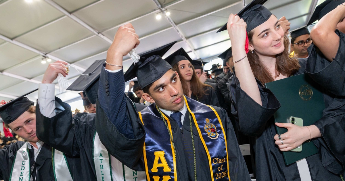 Students moving the tassle on their graduation caps at Commencement