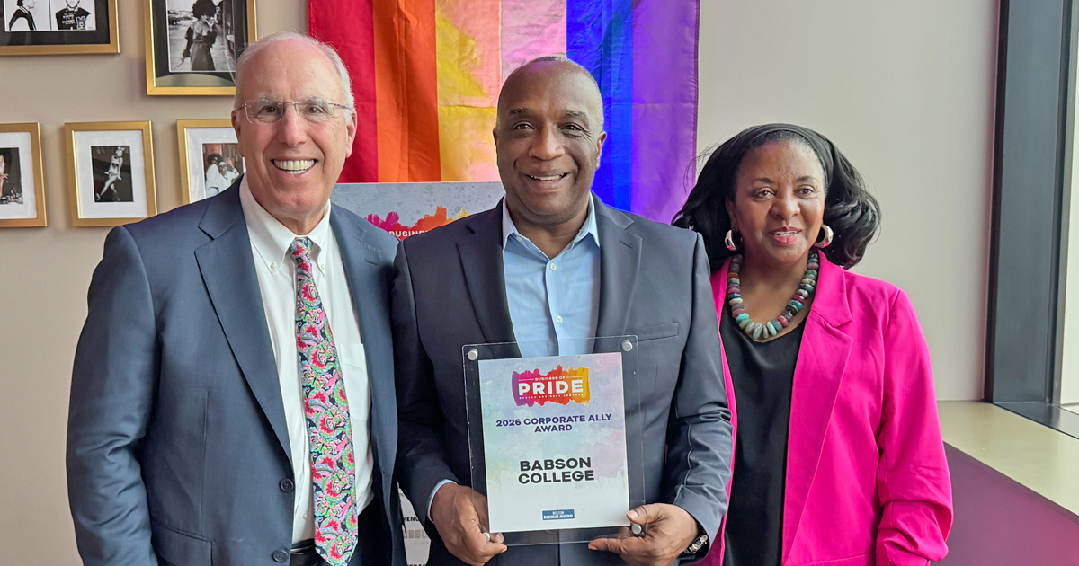 Three people pose for a photo with the award