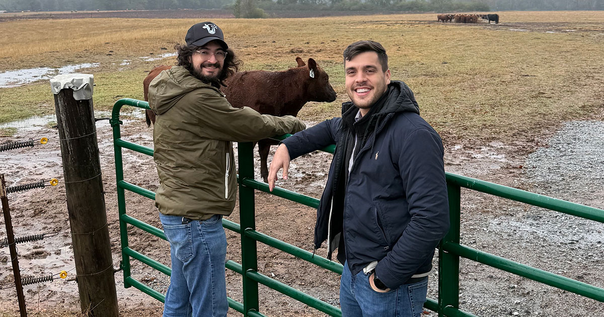 Bryan Ramirez Galindo MSEL’25 and a former employee stand at a fence on a farm