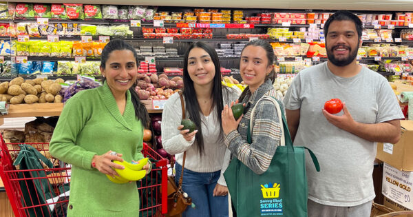 Four people pose for a photo while holding produce at a Trader Joe's