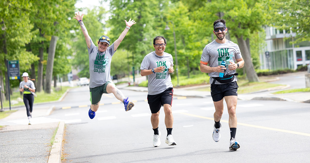 Runners race down the road while one leaps in the air