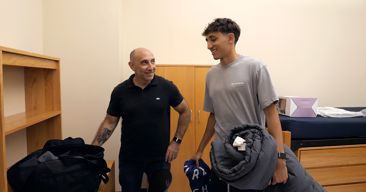 A father and son moving into a college dorm room.