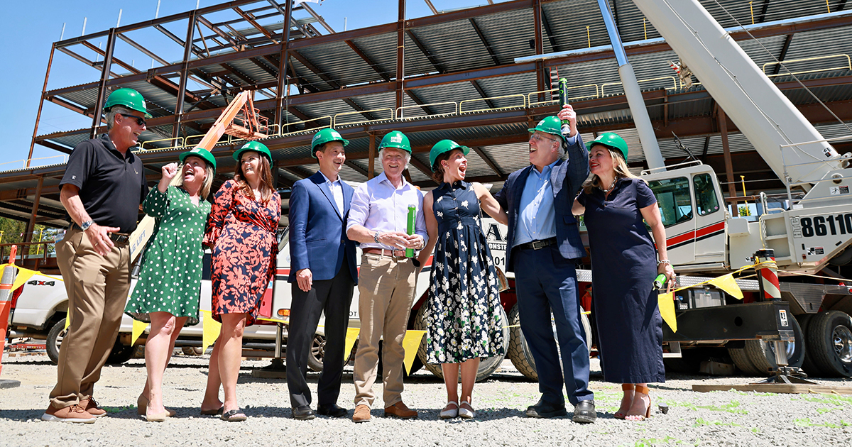 Eight people wearing hard hats pose for a group photo at the construction site