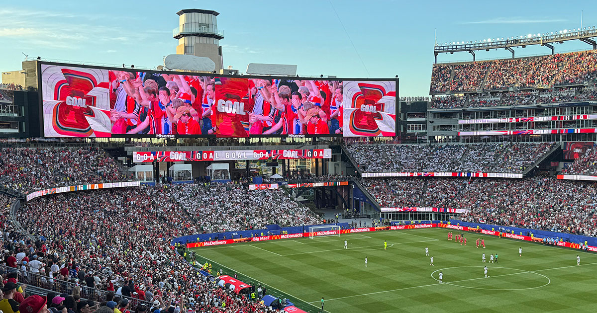 Fans filling a stadium cheer on a goal at a World Cup match