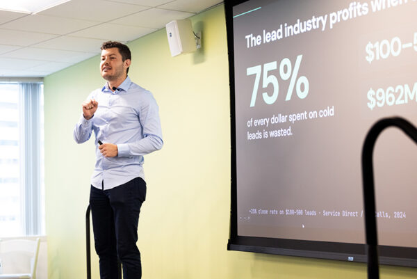 A student entrepreneur gesturing while presenting his venture from the stage.
