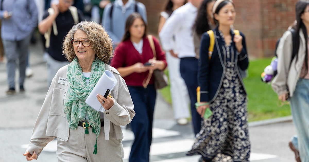 Kate Klepper walks on campus with a crowd of students behind her