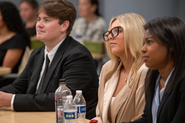 Three students sit at a table in a classroom