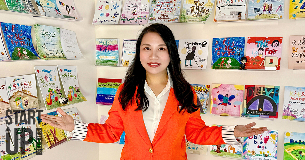 Woman stands in front of several published books