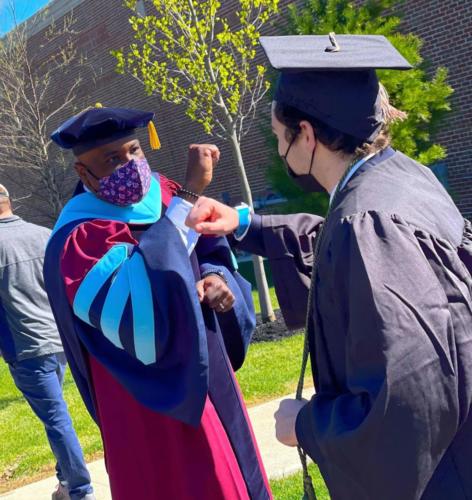 Vice President for Learner Success and Dean of Campus Life Lawrence P. Ward offers a student a fist bump during the commencement procession.